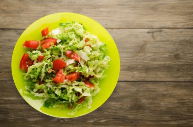  ahşap arka plan üzerinde bir tabakta lahana domates salatası