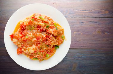 Ahşap arka plan üzerinde bir tabak içinde soğan ile haşlanmış domates 