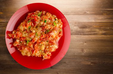 Ahşap arka plan üzerinde bir tabak içinde soğan ile haşlanmış domates 