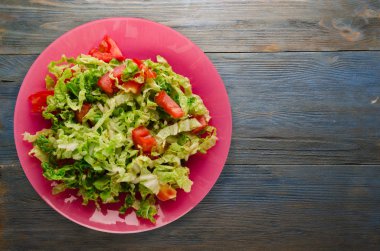  ahşap arka plan üzerinde bir tabakta lahana domates salatası