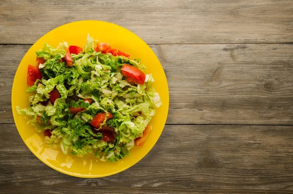 Ahşap arka plan üzerinde bir tabakta lahana domates salatası — Stok fotoğraf