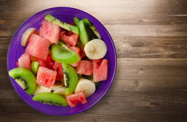 木製の背景に健康な新鮮なフルーツ サラダのプレート — ストック写真