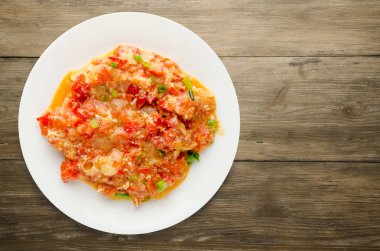 Ahşap arka plan üzerinde bir tabak içinde soğan ile haşlanmış domates 