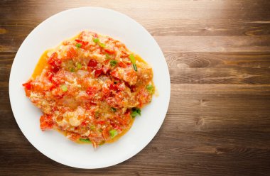 Ahşap arka plan üzerinde bir tabak içinde soğan ile haşlanmış domates 