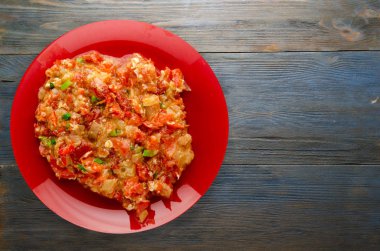 Ahşap arka plan üzerinde bir tabak içinde soğan ile haşlanmış domates. 