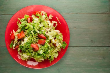  ahşap arka plan üzerinde bir tabakta lahana domates salatası