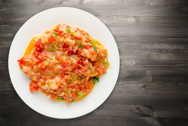 Ahşap arka plan üzerinde bir tabak içinde soğan ile haşlanmış domates 