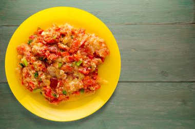 Ahşap arka plan üzerinde bir tabak içinde soğan ile haşlanmış domates 