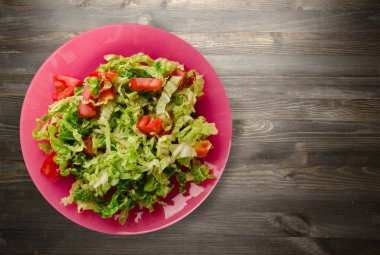  ahşap arka plan üzerinde bir tabakta lahana domates salatası