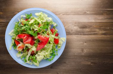  ahşap arka plan üzerinde bir tabakta lahana domates salatası