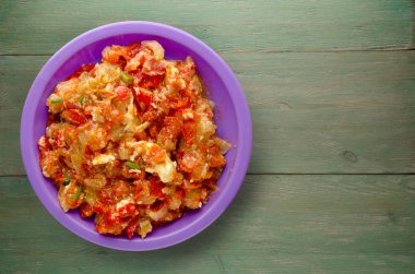 Ahşap arka plan üzerinde bir tabak içinde soğan ile haşlanmış domates 