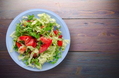  ahşap arka plan üzerinde bir tabakta lahana domates salatası