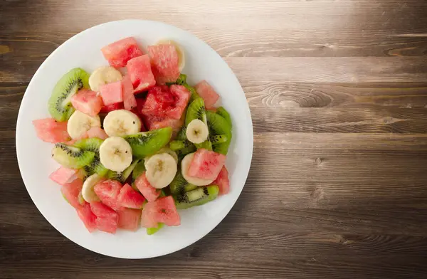 sağlıklı taze meyve salatası ahşap zemin üzerine tabak 