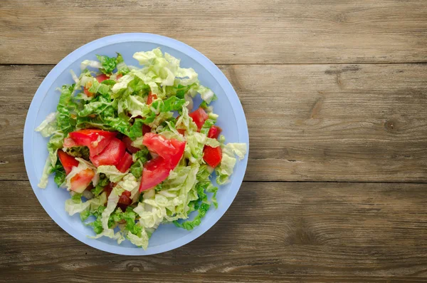 Ahşap arka plan üzerinde bir tabakta lahana domates salatası — Stok fotoğraf