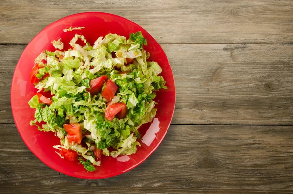 Ahşap arka plan üzerinde bir tabakta lahana domates salatası — Stok fotoğraf