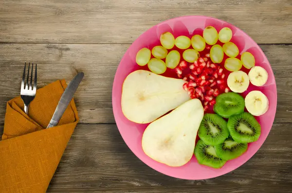 Frukt mix (päron, kiwi, vindruvor, banan, granatäpple) på ett trägolv — Stockfoto