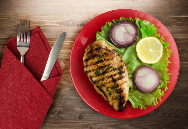 grilled chicken fillet with vegetables (lemon, salad, onion) on