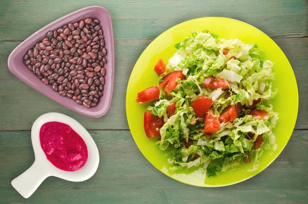 Salade de tomate au chou dans une assiette sur fond de bois — Photo