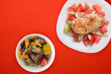 Domates salatası, salatalık ve soğanlı ızgara tavuk göğsü. Koyu kahverengi arka planda beyaz tabakta ızgara tavuk göğsü. Kızarmış tavuk göğsü manzarası