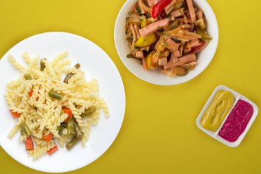 Renkli arka planda sebzeli bir tabakta makarna. Sebze salatası ve soslu Akdeniz yemeği. Sağlıklı yiyecek manzarası. düz yat