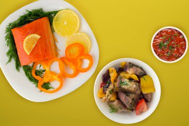 Dereotlu kırmızı balık, biber, beyaz bir tabakta limon...