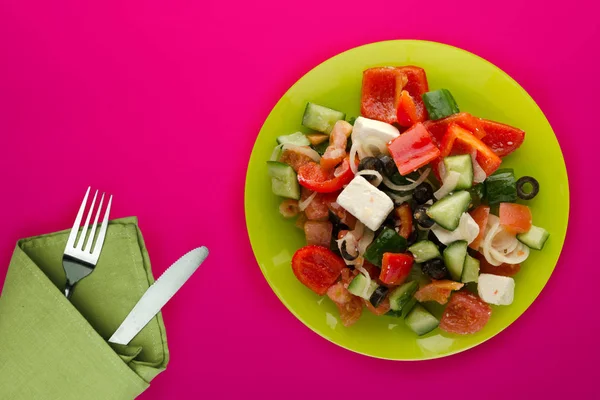 Griekse salade op een rode achtergrond. Griekse salade op een groene plaat t — Stockfoto