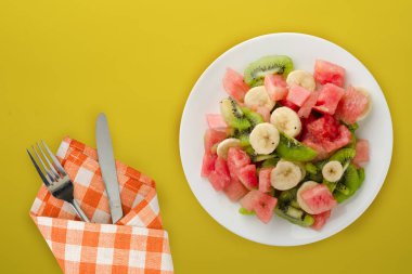  Arka planda beyaz tabakta taze meyve salatası. sağlıklı yiyecekler