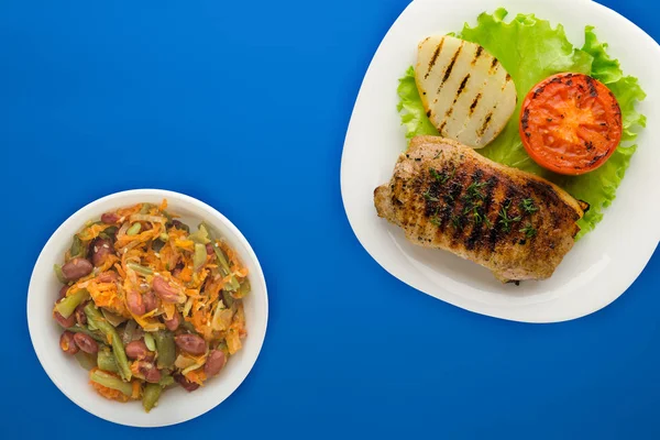 Смажена свинина з картоплею та помідорами на кольоровому фоні — стокове фото