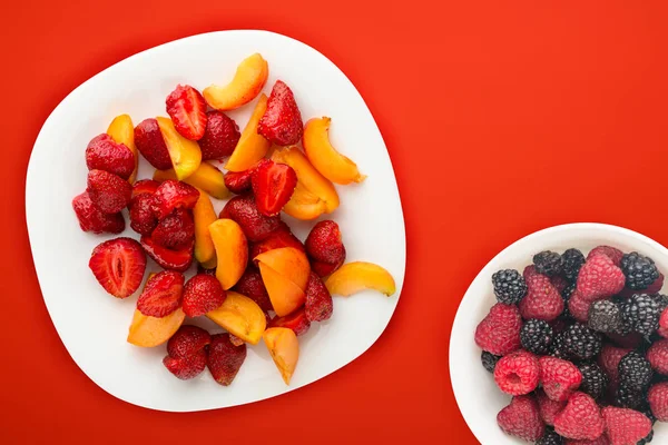 Nourriture saine. Fraises et abricots sur une assiette blanche. frais — Photo