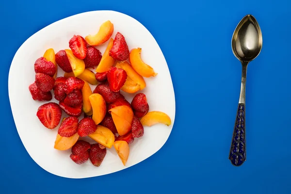 Nourriture saine. Fraises et abricots sur une assiette blanche. frais — Photo