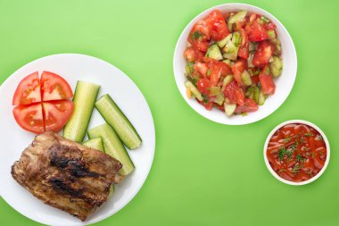 Kızarmış domuz pirzolası, salatalık ve domates.