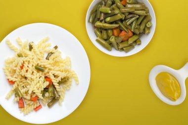 Renkli arka planda sebzeli bir tabakta makarna. Ortam