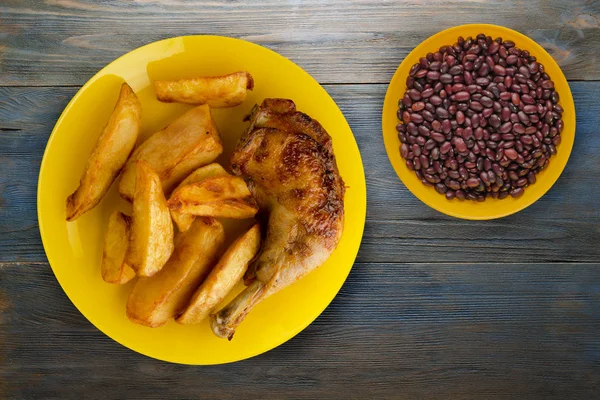 Жареные куриные бедра и картофель фри на тарелке на деревянной бабе — стоковое фото