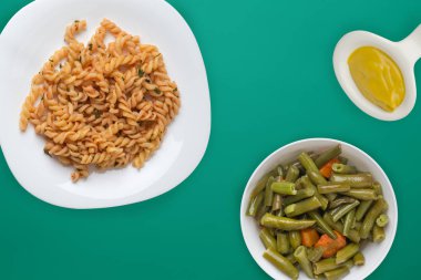 Domates soslu beyaz tabakta makarna ve sebze salatası.