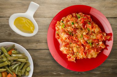 Ahşap arka plan üzerinde bir tabak içinde soğan ile haşlanmış domates 