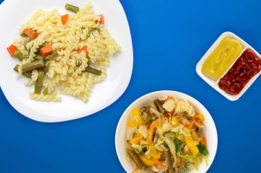 Renkli arka planda sebzeli bir tabakta makarna. Ortam