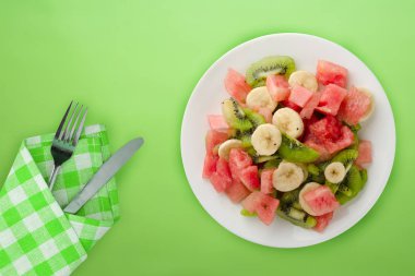  Arka planda beyaz tabakta taze meyve salatası. sağlıklı yiyecekler