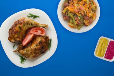 Kızarmış tavuk budu ve sebzeli beyaz tabak ve...