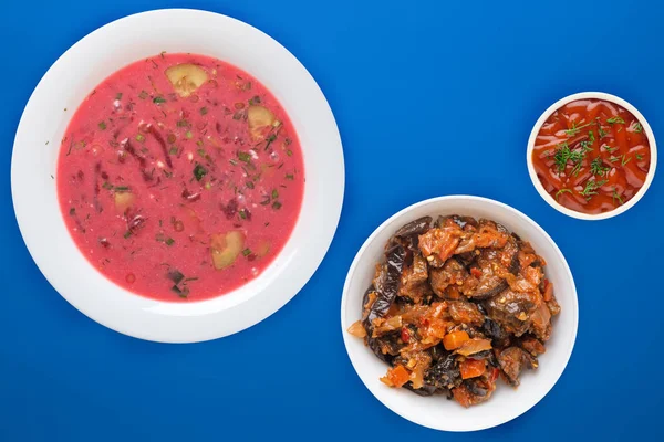 Rote-Bete-Suppe ein weißer Teller mit Gemüsesalat auf einem farbigen Ba — Stockfoto