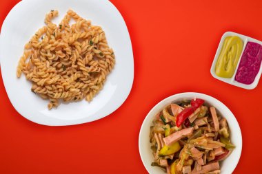 Domates soslu beyaz tabakta makarna ve sebze salatası.