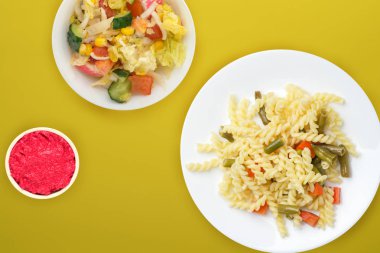 Renkli arka planda sebzeli bir tabakta makarna. Ortam