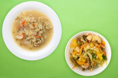 Beyaz bir tabakta renkli bir arka planda lahana çorbası. Çorba ile