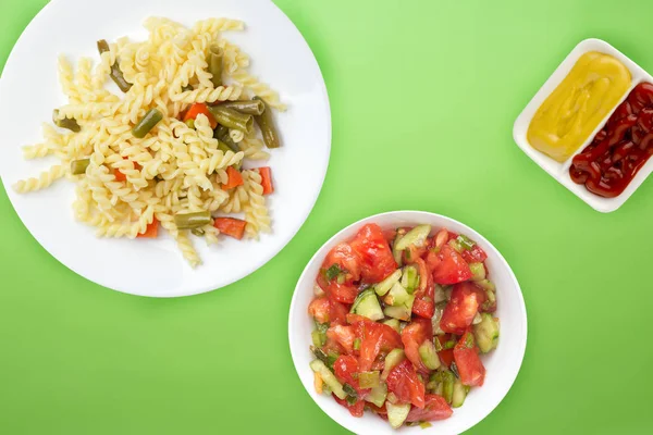 Pasta op een bord met groenten op een gekleurde achtergrond. Mediet — Stockfoto