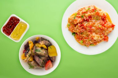 Renkli arka planda beyaz bir tabakta soğanlı haşlanmış domates. Soğan manzaralı haşlanmış domates. vejetaryen yemeği.