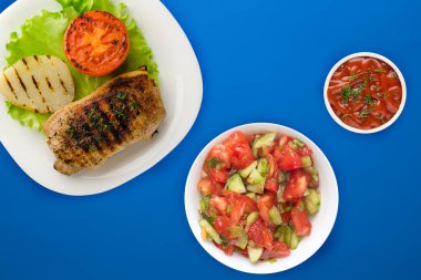 Renkli arka planda patates ve domatesli ızgara domuz eti. Salata ve soslu kızarmış domuz eti.
