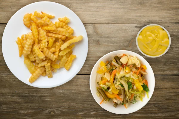 Patatas en un plato blanco en el fondo. papas fritas con ensalada de verduras vista superior comida rápida. alimentos poco saludables —  Fotos de Stock