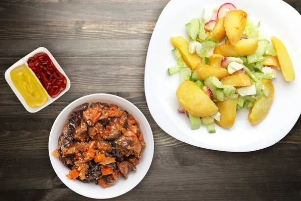 Kartoffelkeile mit Gemüse auf einem weißen Teller auf einem hölzernen Hintergrund. ungesunde Ernährung. Rustikales Essen. . — Stockfoto