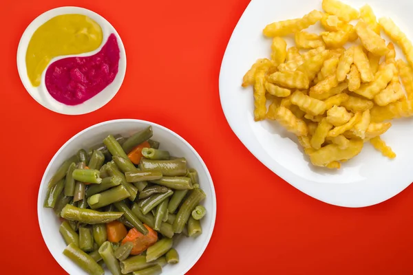 Patatas en un plato blanco en el fondo. papas fritas con ensalada de verduras vista superior comida rápida. alimentos poco saludables —  Fotos de Stock
