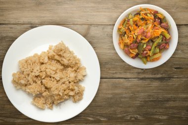 Beyaz tabakta soya soslu beyaz pirinç. Ahşap arka planda sebze salatalı pirinç..