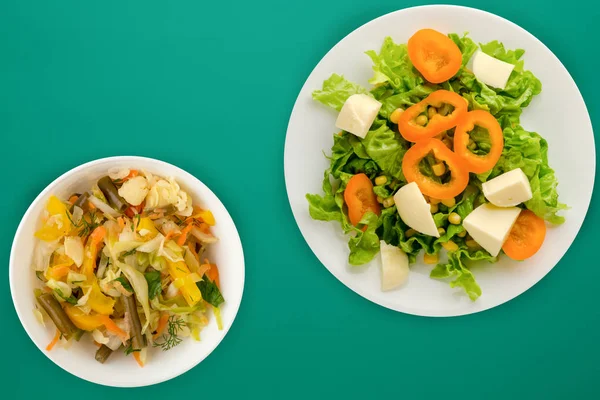 Salad of cheese, lettuce, corn, pepper on a colored background. Vegetarian salad on a white plate. Vegetarian salad top view — 스톡 사진